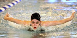 Swimmer facing forward, doing a butterfly stroke in pool