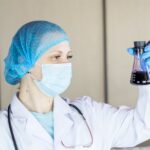 Chemical engineer student in lab coat looking at experiment