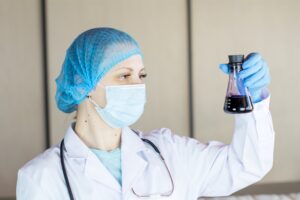Chemical engineer student in lab coat looking at experiment