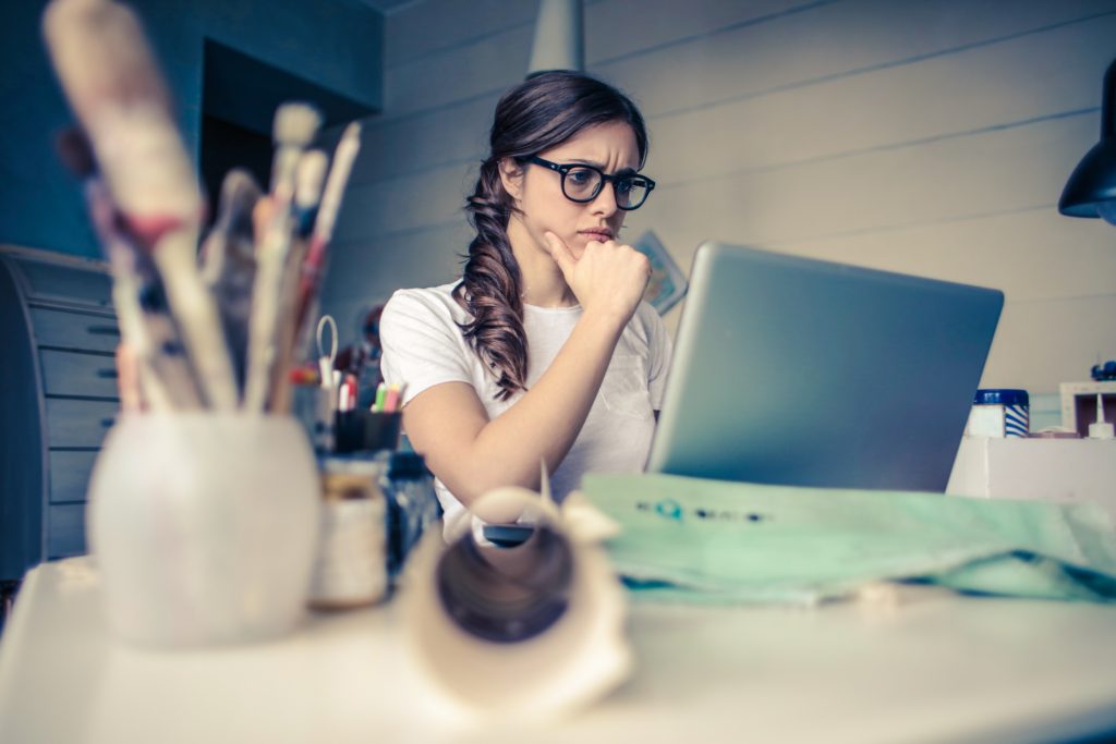 Women with glasses thinking in front of laptop.